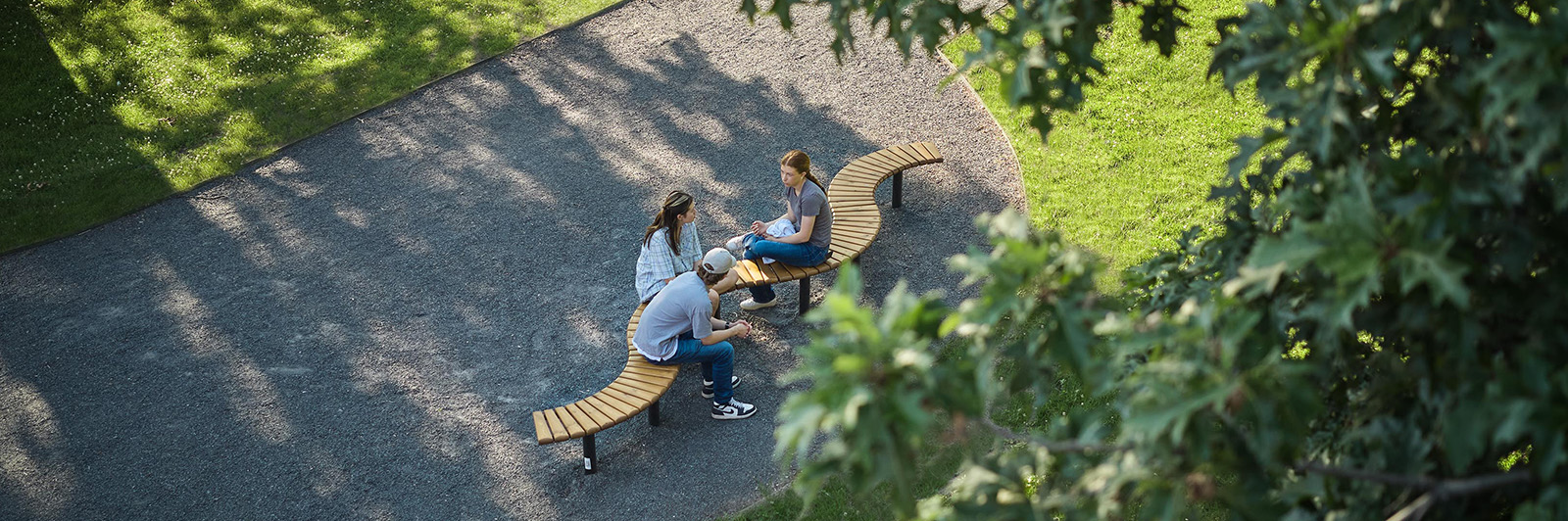 Tři teenageři sedící na lavičce Sofiero v zeleném park.
